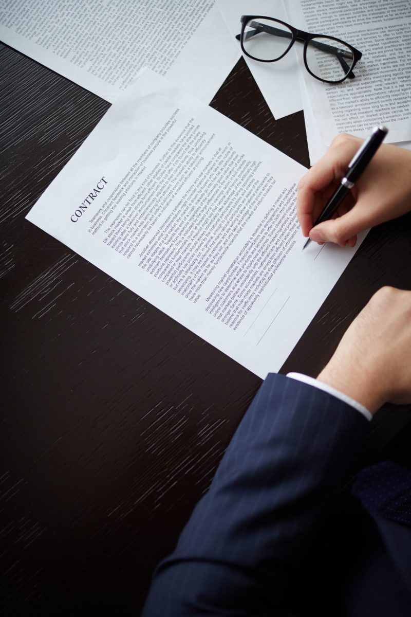 Image of businessman hand with pen signing contract at workplace